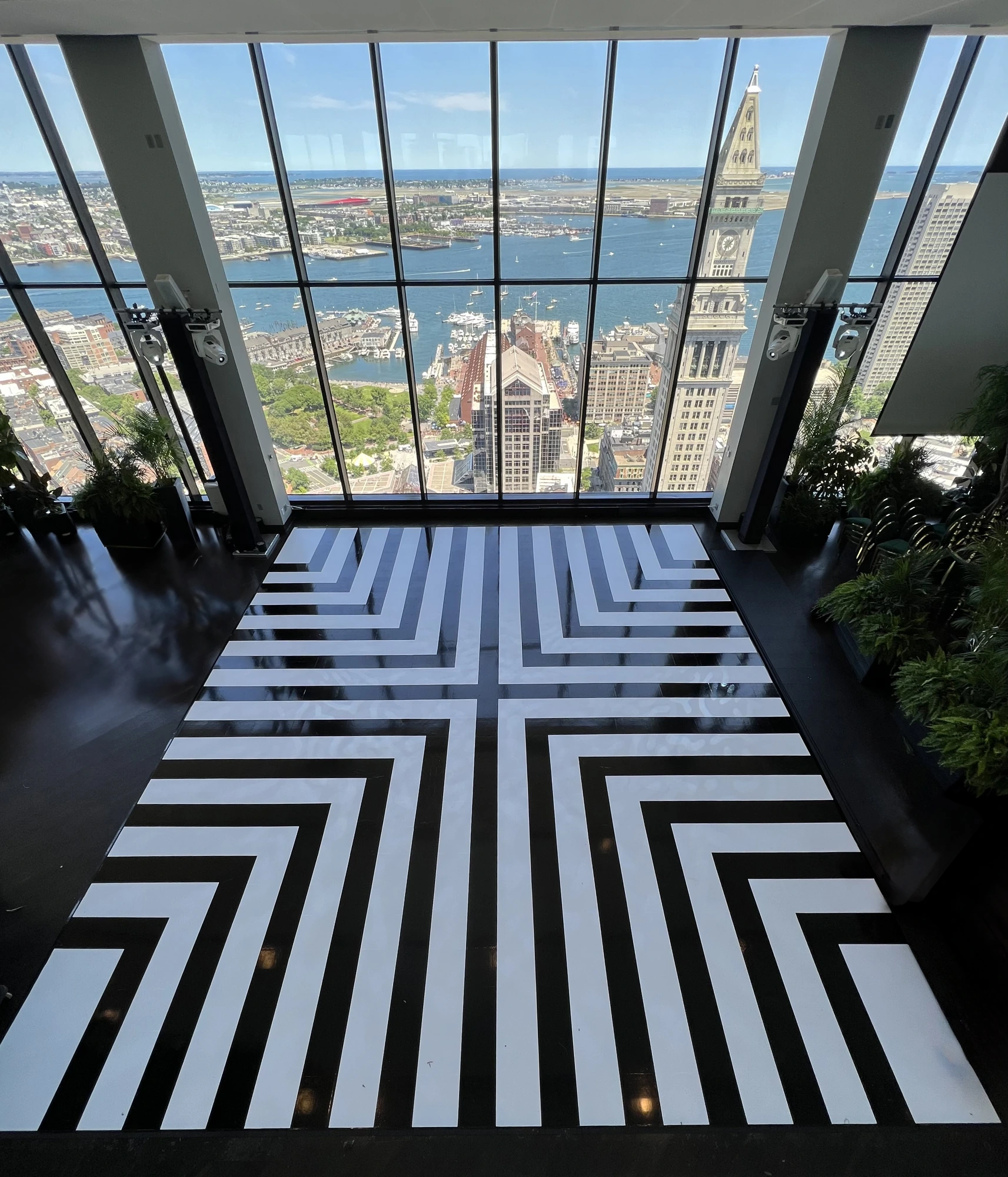 Black and white patterned dancefloor overlooking the Boston harbor skyline through floor-to-ceiling windows