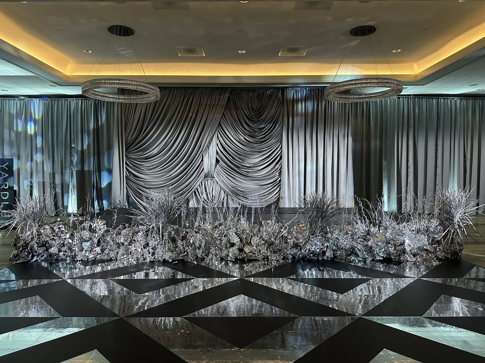 Black and silver mirror dancefloor with geometric pattern under crystal chandeliers
