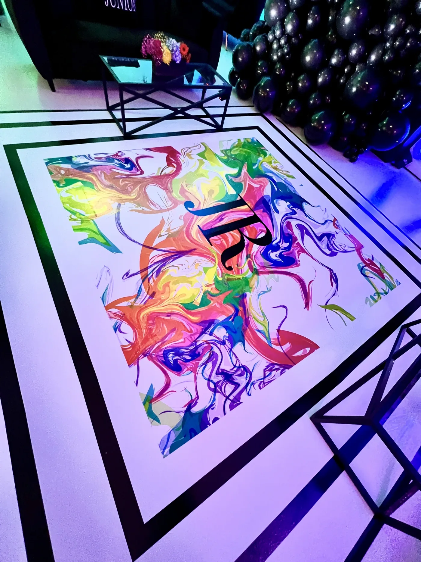 Custom printed dancefloor with colorful painterly swirl artwork and black monogram