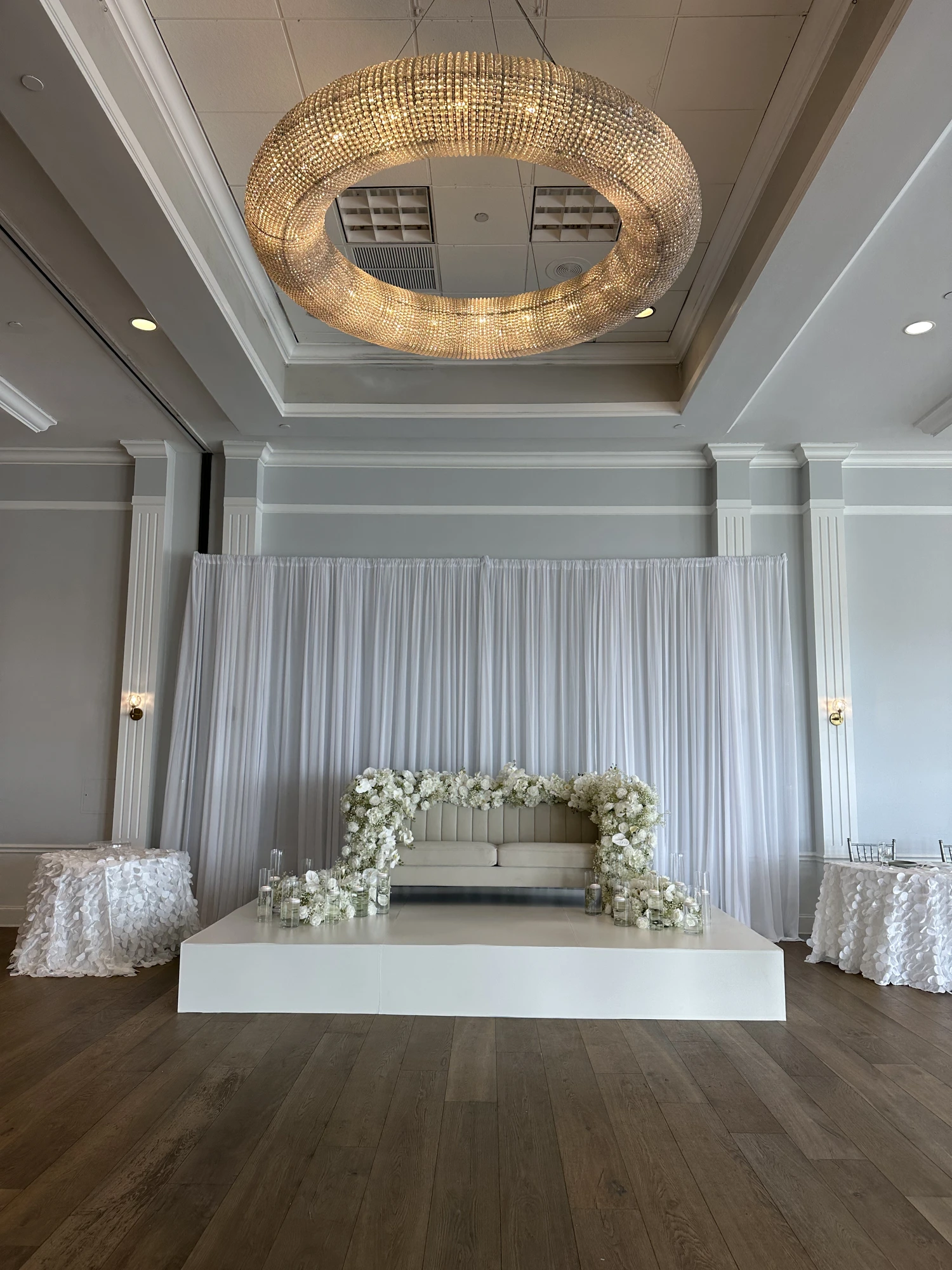 After — a custom white-wrapped stage with floral backdrop and drapery